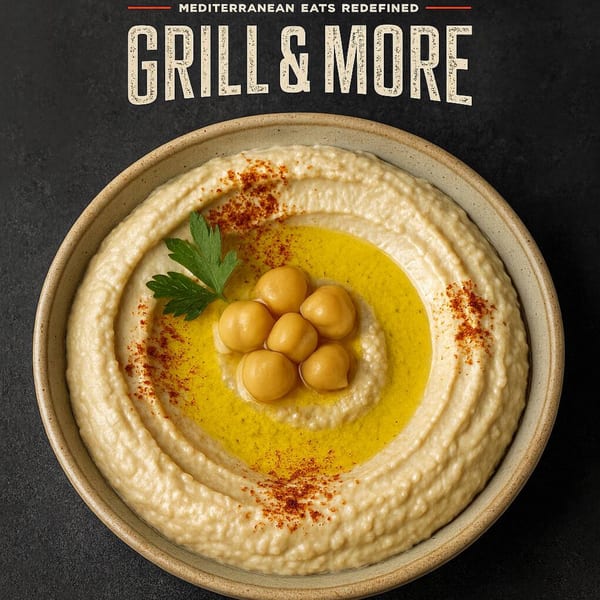 A bowl of creamy hummus, garnished with chickpeas, olive oil, paprika, and parsley.