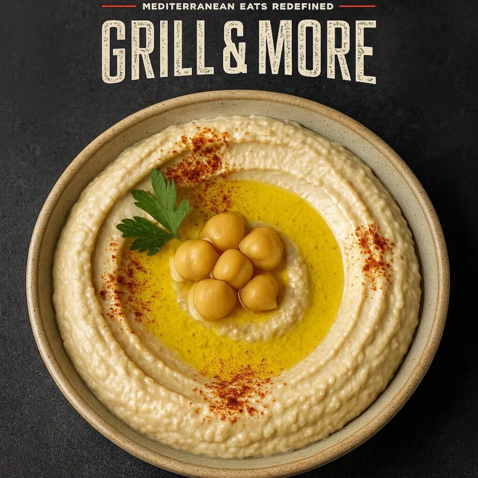 A bowl of creamy hummus, garnished with chickpeas, olive oil, paprika, and parsley.